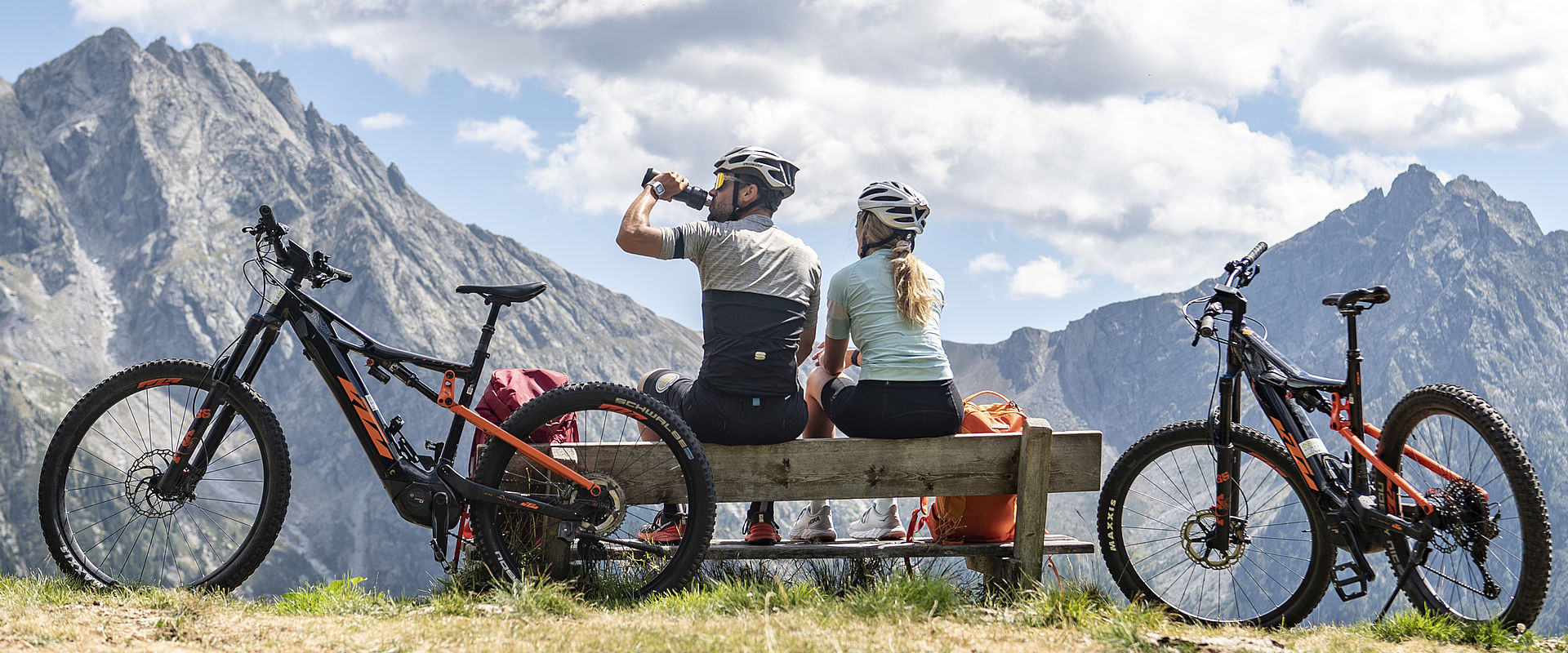 Paar sitzt auf Bank in Berglandschaft mit Räder geparkt