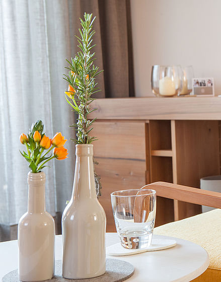 Vasen mit orangen Blumen auf kleinen Tisch im Hotel Hohenwart