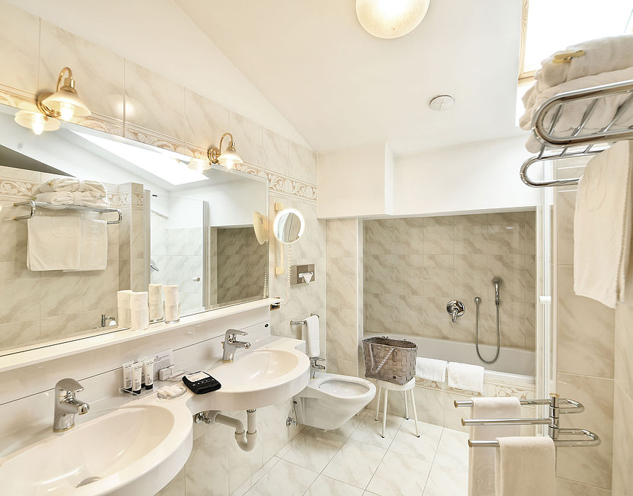 Marmor Fliesen Badezimmer mit Badewanne, Dusche, Toilette, Bidet, zwei Waschbecken und Spiegel