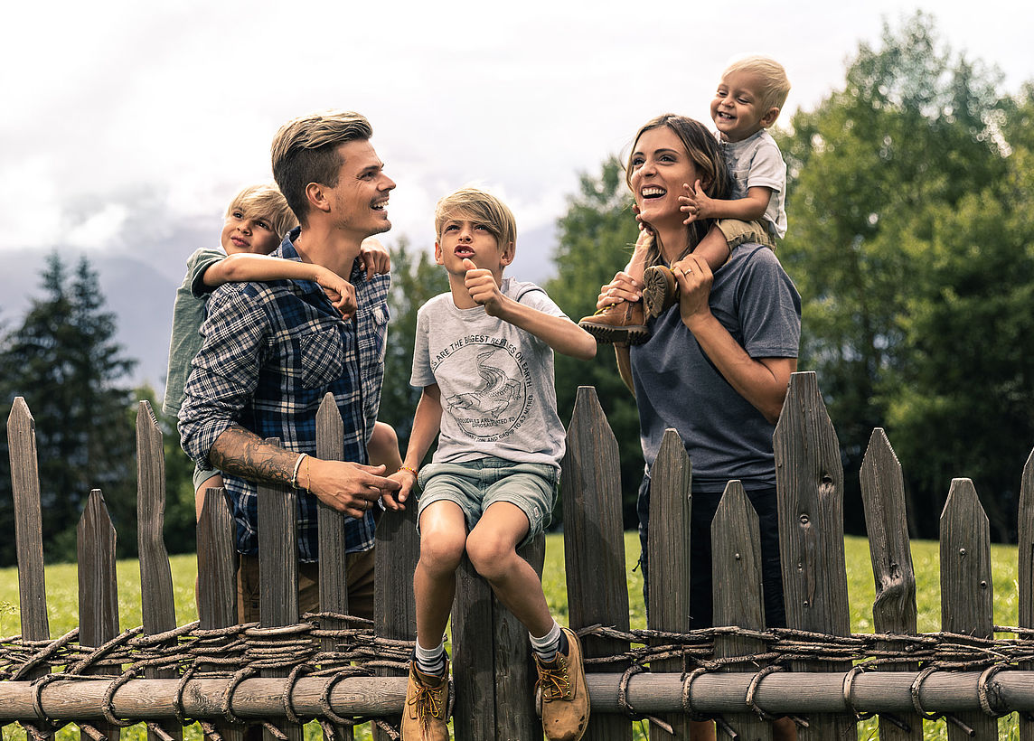 Familie lacht auf Zaun bei Südtiroler Familienurlaub 