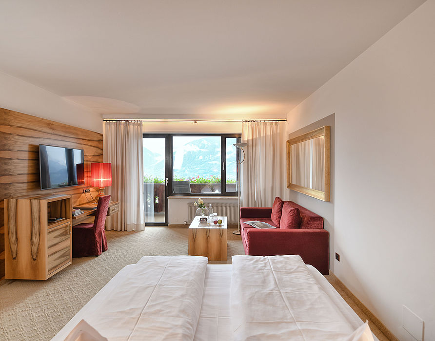 Double bed with view of red sofa, Tv and balcony