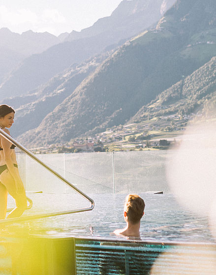 Donna entra nella piscina con vista sulle montagne dell'albergo benessere Alto Adige vicino a Merano