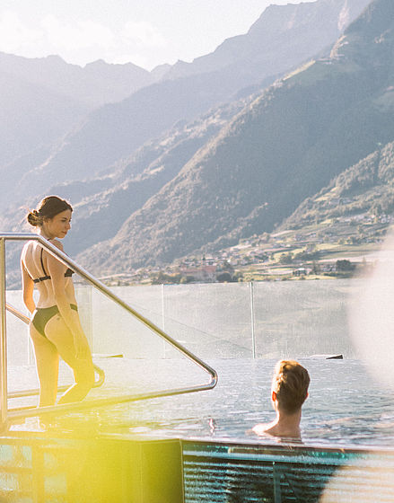 Frau geht in Swimmingpool mit Ausblick auf Berge im Wellnesshotel Südtirol bei Meran