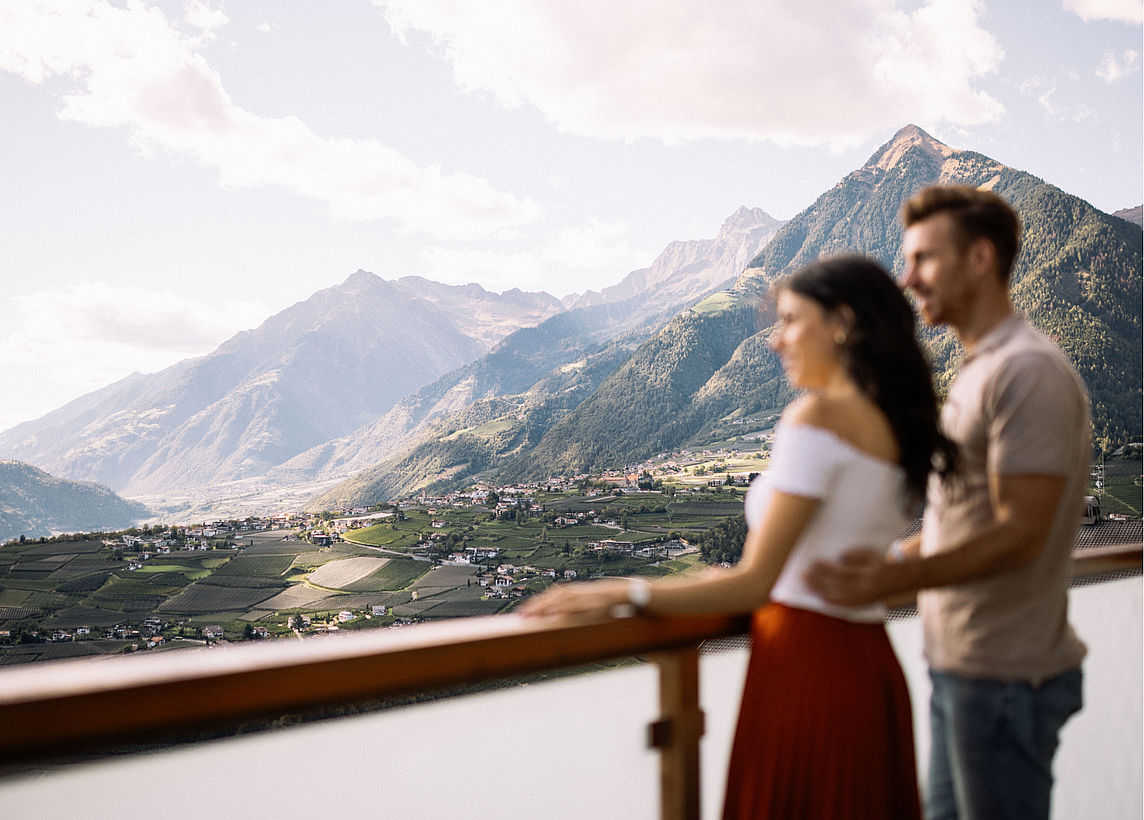 Paar sind auf Terasse mit Ausblick auf Berglandschaft im Wellnesshotel Südtirol bei Meran