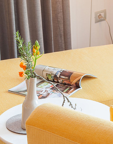 Gelbes Sofa mit kleinen Tisch mit Blumen im Hotel Hohenwart