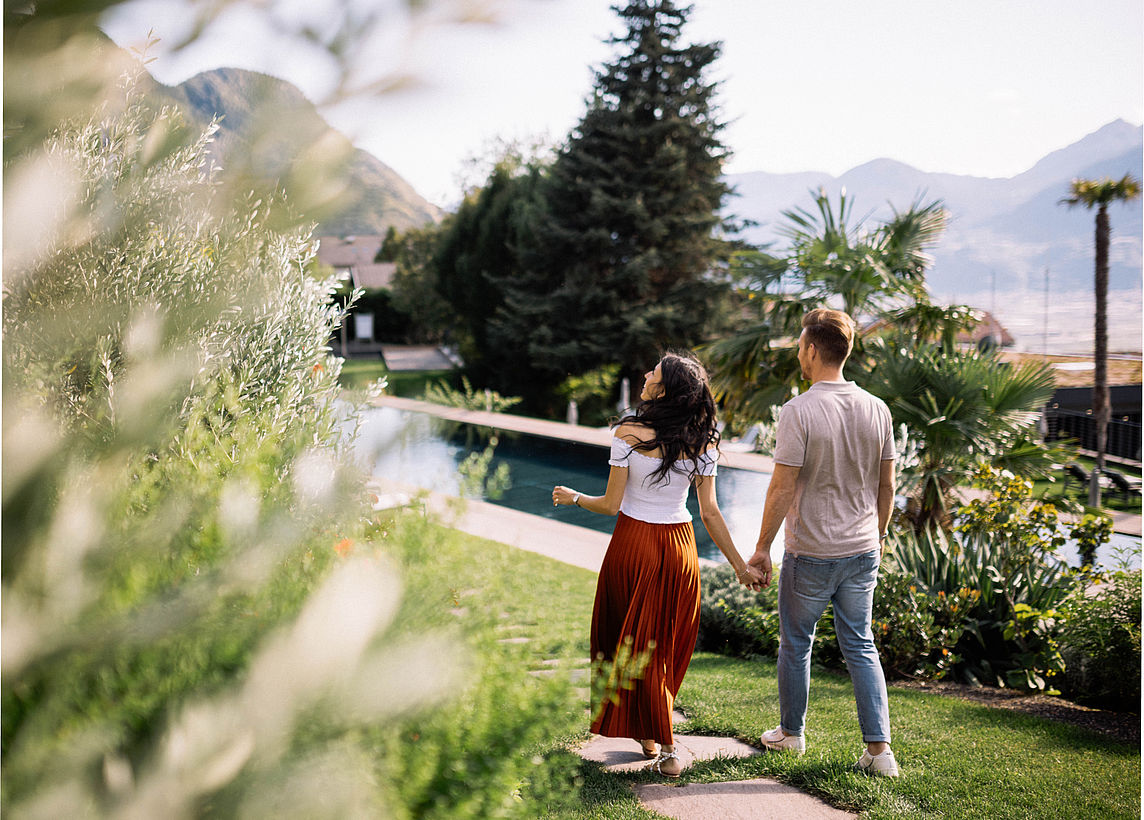Coppia a passeggio nel giardino dell’albergo benessere Alto Adige vicino a Merano