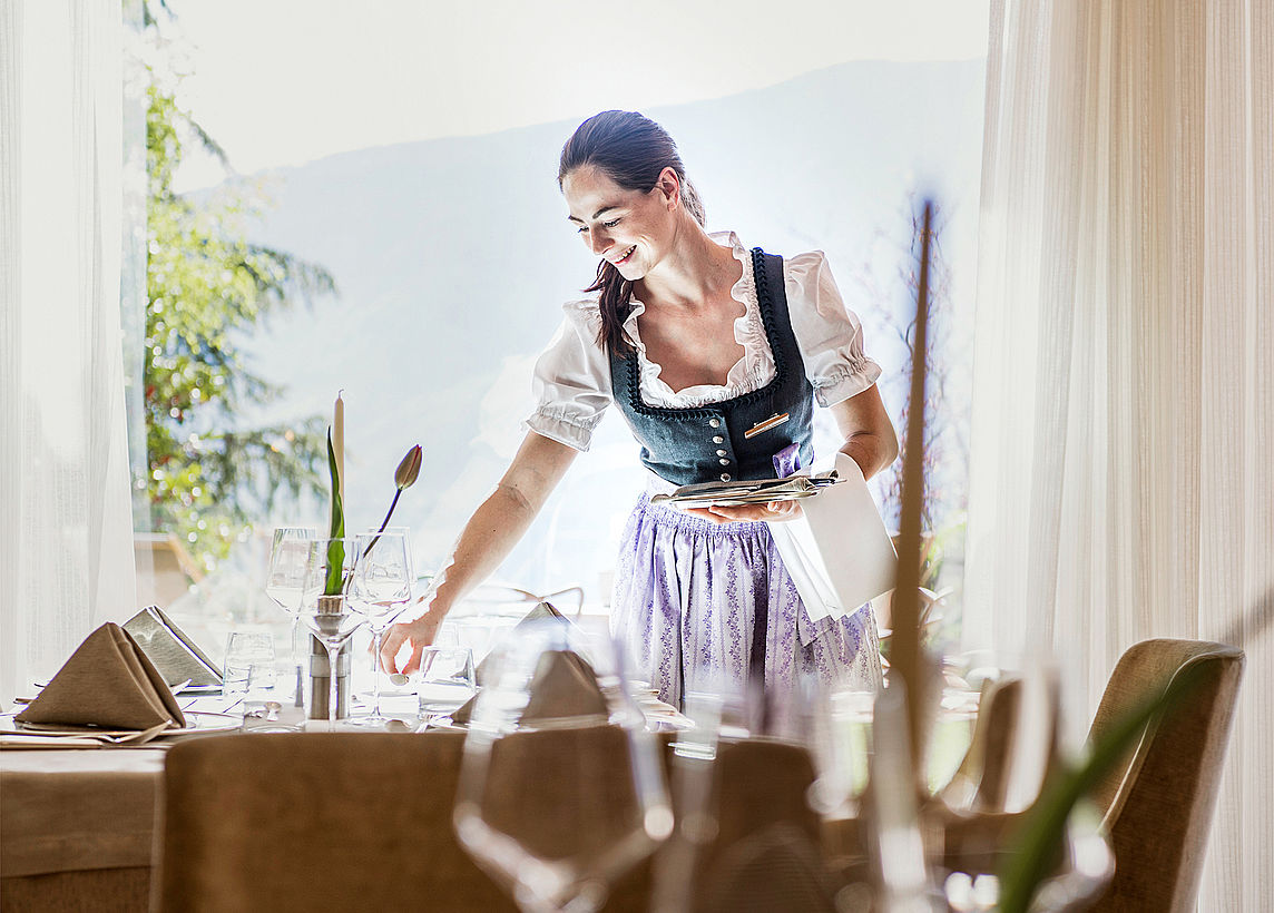 Woman sets the table at the wellness hotel near Merano