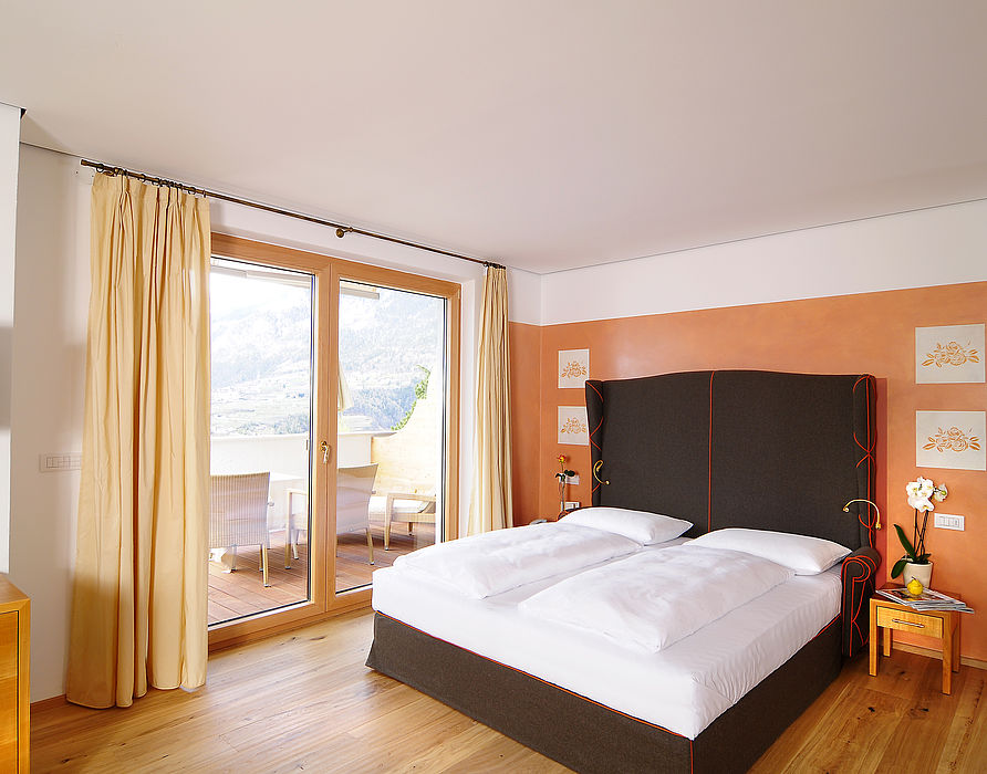 Schwarzes Doppelbett mit weißer Bettwäsche und oranger Wand