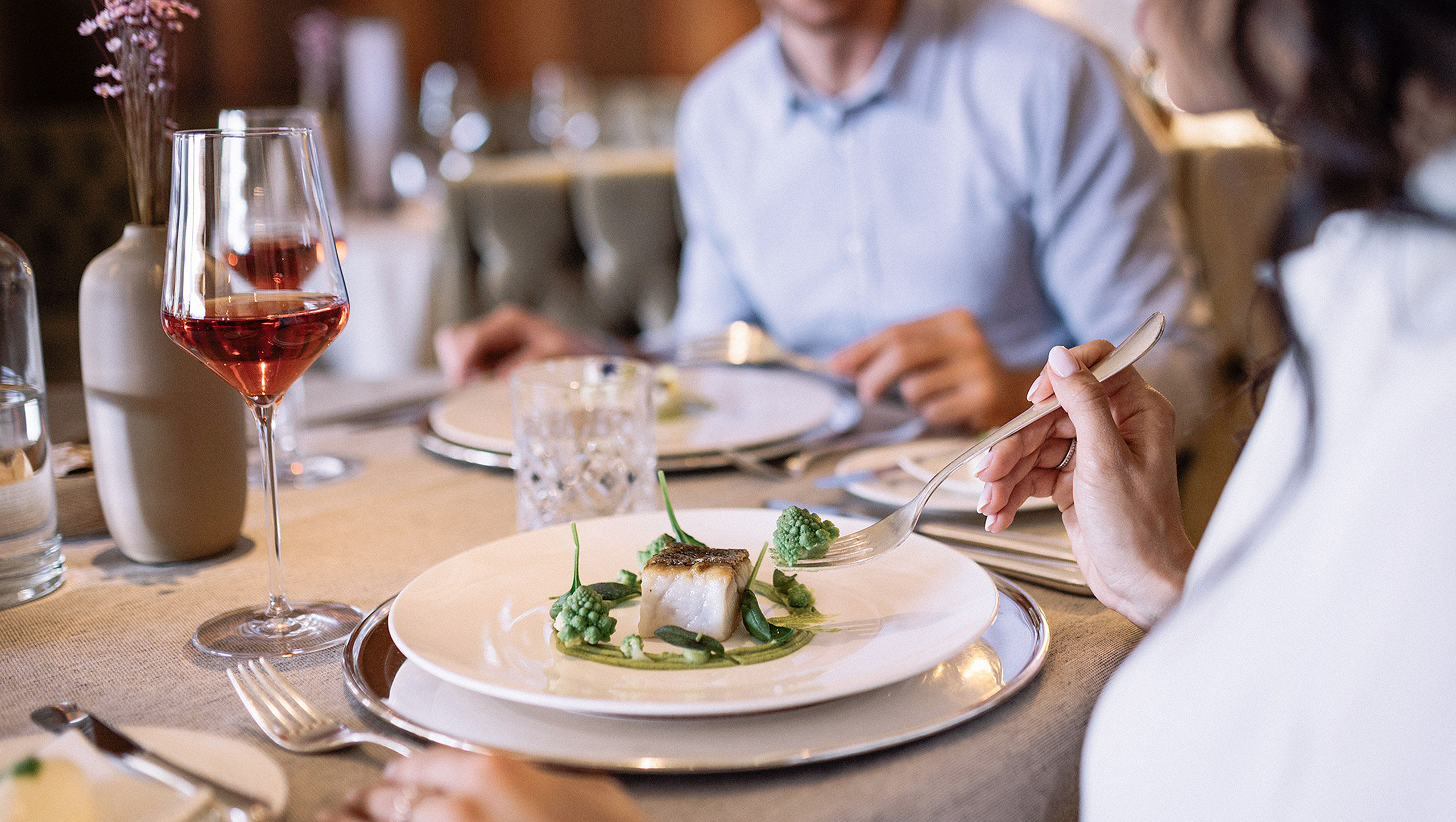 Una coppia mangia un piatto di pesce e beve vino all’albergo benessere Scena