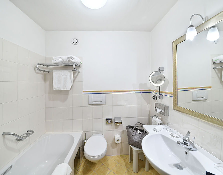 Badezimmer mit gelbe Bodenfliesen, Badewanne, großes Waschbecken und Toilette