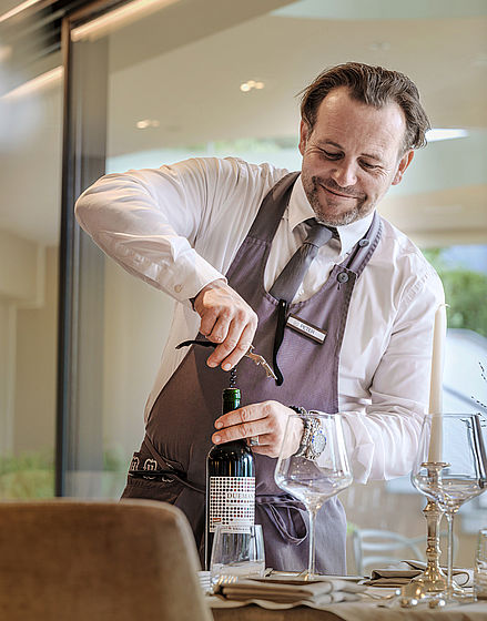 Kellner öffnet Wein im Weinspezialitäten Hotel