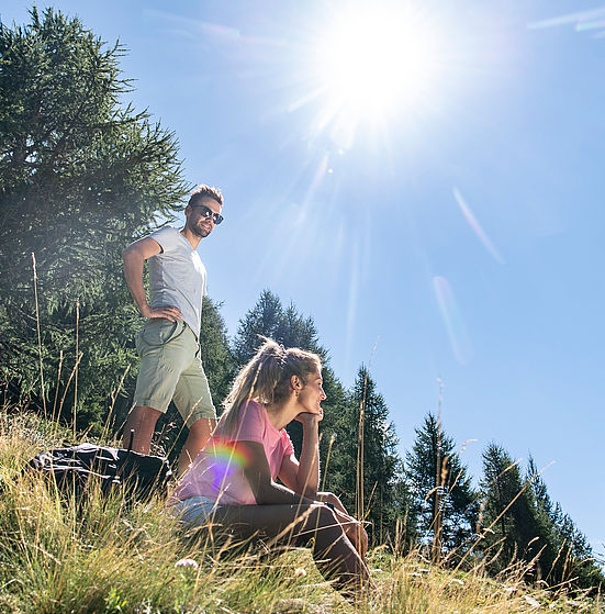 Couple is hiking, woman is sitting on the ground