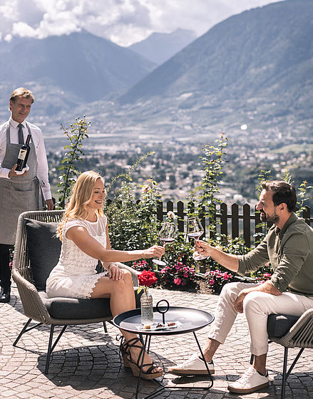 Una coppia si gode il vino con vista all’albergo benessere Alto Adige vicino a Merano