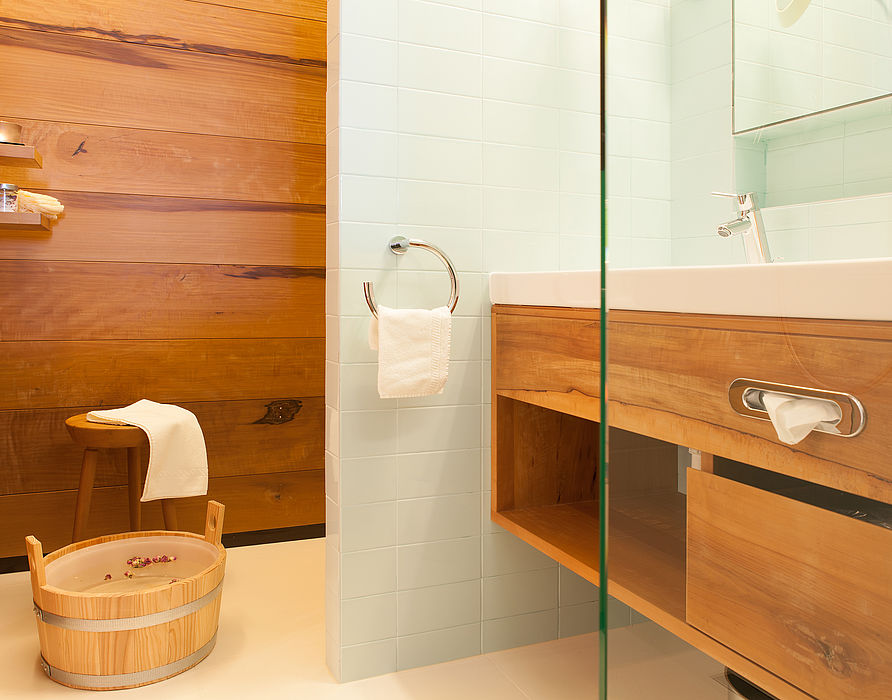 Holzverkleidetes Badezimmer mit weißen Waschbecken und minzfarbigen Fliesen