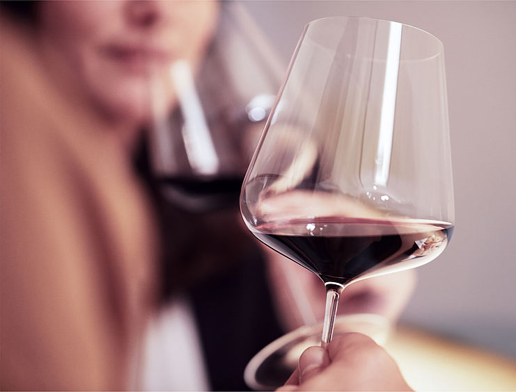 Donna che beve vino rosso da un bicchiere