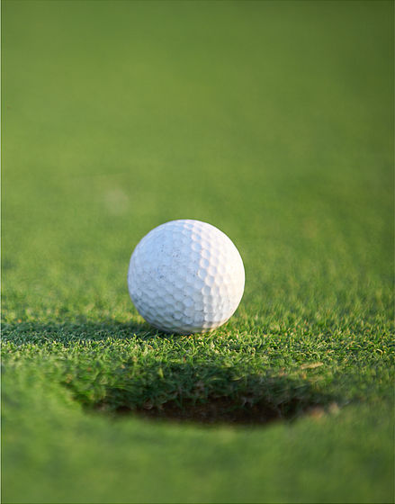 Golfball neben dem Loch im Golf Hotel