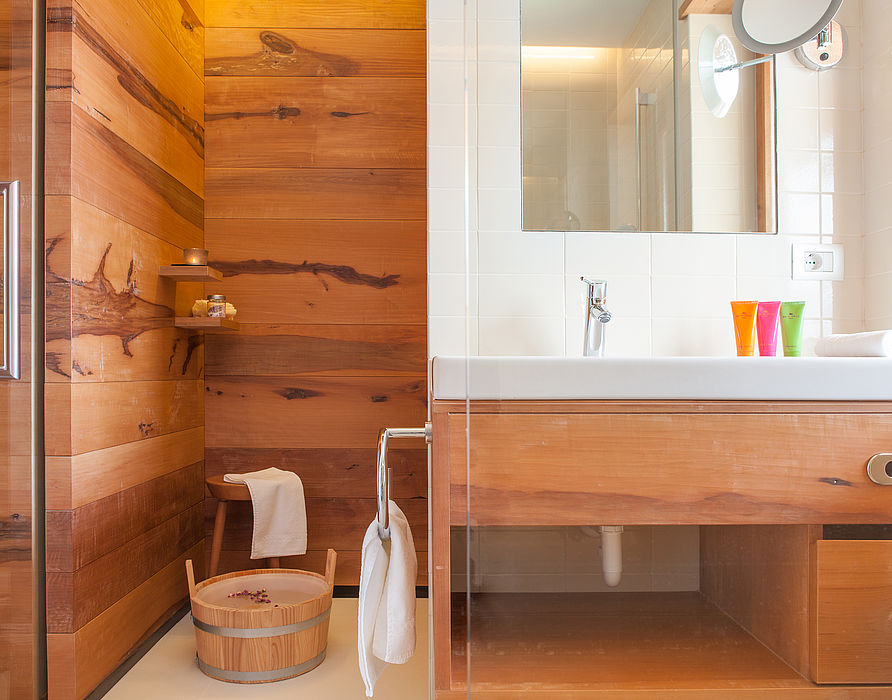 Holzverkleidetes Badezimmer mit weißen Waschbecken und Spiegel
