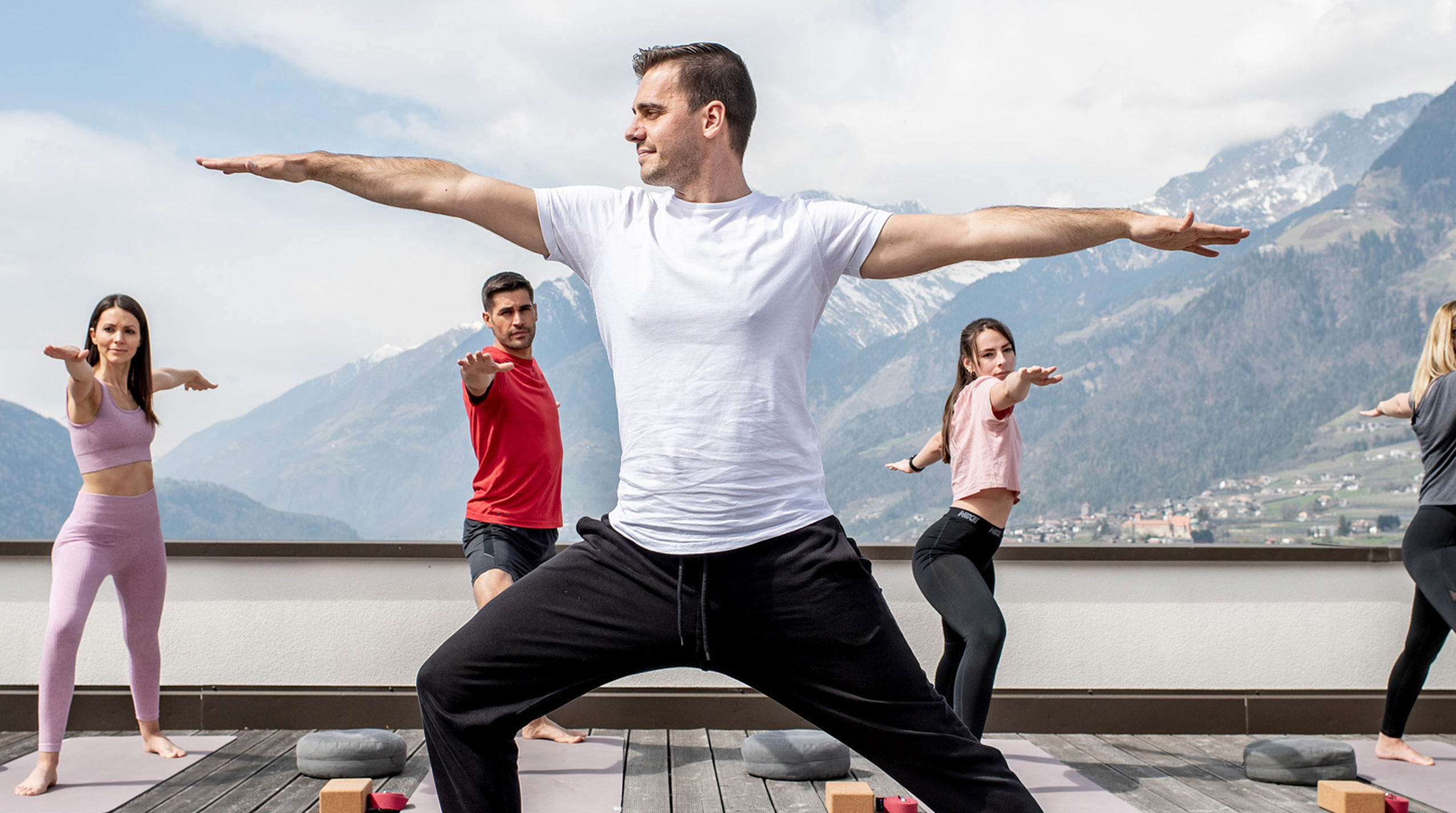 Man in white T-shirt shows yoga pose, other four follow suit